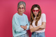 Leinwandbild Motiv Playful mother and adult daughter in funky eyeglasses standing against pink background