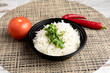 an Indian rice in a dish with cilantro and a hot pepper on a rattan place mat
