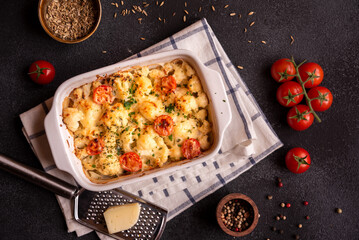 Baked cauliflower cooked with tomatoes and creamy cheese, healthy vegetable meal