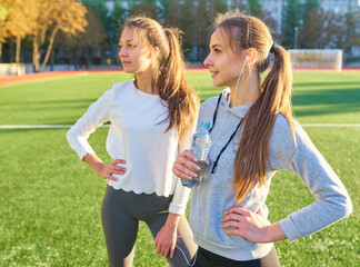 Two girls in sportswear posing at the stadium.Portrait of two sports girlfriends at the sports stadium.