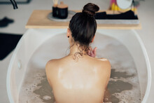 Young Woman Embracing Herself Taking A Bath View From The Back