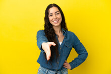 Young Caucasian Woman Isolated On Yellow Background Shaking Hands For Closing A Good Deal