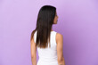 © luismolinero - Young caucasian woman isolated on purple background in back position and looking side
