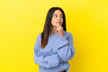 Poster - Young caucasian woman isolated on yellow background having doubts and thinking