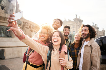 Wall Mural - Diverse cultures students taking selfie with mobile phone outdoors. University college people having fun together