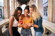 © CarlosBarquero - Three multiracial women using mobile phone outdoors. Youth and social media networking.