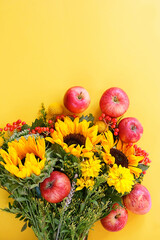 ripe apples and autumn bouquet of sunflowers on yellow background. fall season. symbol of autumn holiday - thanksgiving, mabon, harvest concept. top view. copy space