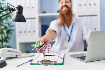 Wall Mural - Young redhead man wearing doctor uniform prescribe pills at clinic