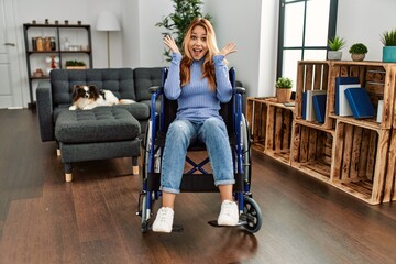 Poster - Young beautiful woman sitting on wheelchair at home celebrating crazy and amazed for success with arms raised and open eyes screaming excited. winner concept