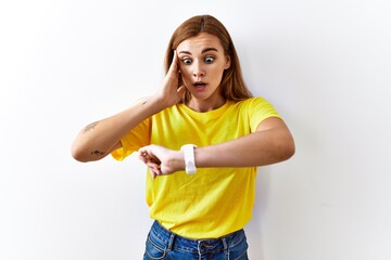 Sticker - Young brunette woman standing over isolated background looking at the watch time worried, afraid of getting late