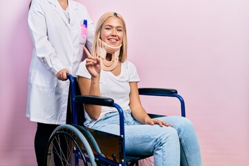 Poster - Beautiful blonde woman sitting on wheelchair with collar neck showing and pointing up with finger number one while smiling confident and happy.