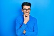 © Krakenimages.com - Young hispanic man wearing casual clothes and glasses looking confident at the camera smiling with crossed arms and hand raised on chin. thinking positive.
