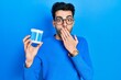 © Krakenimages.com - Young hispanic man holding earwax cotton remover covering mouth with hand, shocked and afraid for mistake. surprised expression