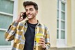 © Krakenimages.com - Handsome hispanic man smiling happy and confident at the city speaking on the phone and drinking a cup of coffee