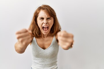 Canvas Print - Beautiful caucasian woman standing over isolated background angry and mad raising fists frustrated and furious while shouting with anger. rage and aggressive concept.