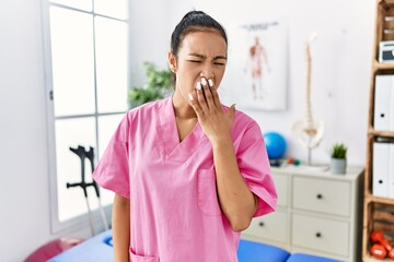 Sticker - Young hispanic woman working at pain recovery clinic bored yawning tired covering mouth with hand. restless and sleepiness.