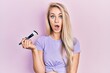 © Krakenimages.com - Young caucasian woman holding makeup brush scared and amazed with open mouth for surprise, disbelief face