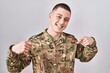 © Krakenimages.com - Young man wearing camouflage army uniform looking confident with smile on face, pointing oneself with fingers proud and happy.