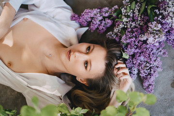 a sexy topless blonde in a white shirt on the floor with lilac flowers