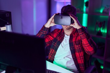 Poster - Young caucasian man streamer playing video game using virtual reality glasses at gaming room