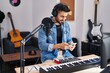© Krakenimages.com - Young hispanic man artist smiling confident using smartphone at music studio