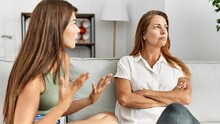 Mother And Daughter Unhappy Arguing Sitting On Sofa At Home
