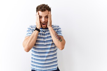 Sticker - Handsome young man standing over isolated background afraid and shocked, surprise and amazed expression with hands on face