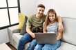 © Krakenimages.com - Young hispanic couple smiling happy using laptop sitting on the sofa  with dog at home.