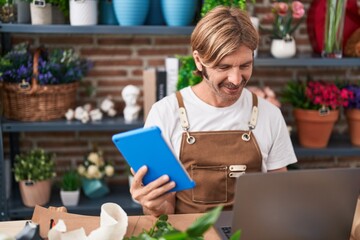 Sticker - Young blond man florist smiling confident using laptop and touchpad at flower shop