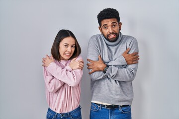 Poster - Young hispanic couple standing together shaking and freezing for winter cold with sad and shock expression on face