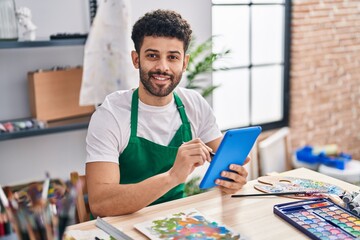 Wall Mural - Young arab man artist smiling confident using touchpad at art studio