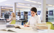 © JackF - Thoughtful woman working with textbook and laptop in library. High quality photo