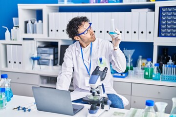 Sticker - Young hispanic man scientist using laptop holding test tube at laboratory