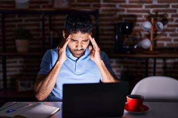 Poster - Hispanic man with beard using laptop at night with hand on head for pain in head because stress. suffering migraine.