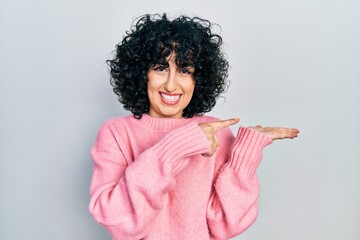 Canvas Print - Young middle east woman wearing casual clothes amazed and smiling to the camera while presenting with hand and pointing with finger.