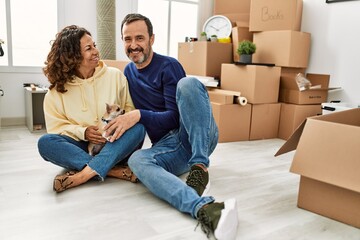 Sticker - Middle age hispanic couple smiling happy sitting on the floor with dog at new home.