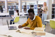 © JackF - Confident african-american man working on laptop in public library. High quality photo