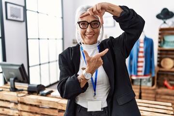 Wall Mural - Middle age grey-haired woman working as manager at retail boutique smiling making frame with hands and fingers with happy face. creativity and photography concept.