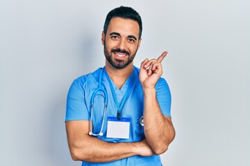 Poster - Handsome hispanic man with beard wearing doctor uniform smiling happy pointing with hand and finger to the side