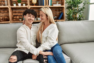 Wall Mural - Young couple sitting on the sofa hugging at home.