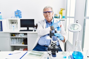 Sticker - Senior caucasian man working at scientist laboratory pointing with hand finger to the side showing advertisement, serious and calm face