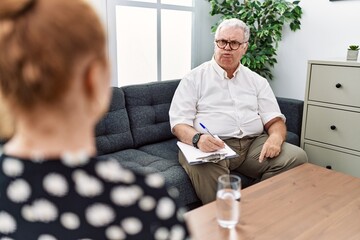 Canvas Print - Senior psychologist man at consultation office puffing cheeks with funny face. mouth inflated with air, crazy expression.