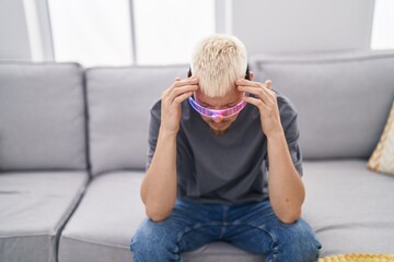 Wall Mural - Young caucasian man wearing virtual reality glasses suffering from headache desperate and stressed because pain and migraine. hands on head.