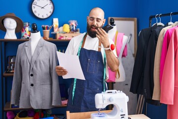 Poster - Young bald man tailor talking on smartphone looking clothing design at clothing factory