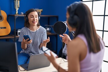 Sticker - Two women musicians listening to music using smartphone at music studio