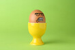 Leinwandbild Motiv Egg with drawn angry face in cup on green background