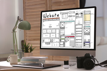Computer with sketch of website planning and design on white table