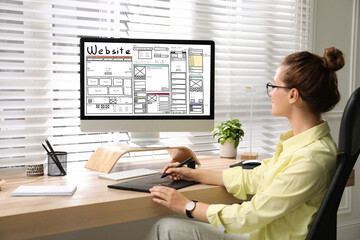 Designer creating website on computer at wooden table