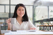 © wattana - Millennial businesswoman sitting at her workplace with financial document and smiling to camera.