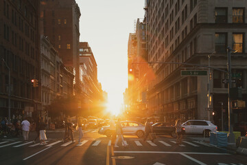 Wall Mural - Crowds of people and cars in the busy intersection of 23rd Street and 5th Avenue in New York City with light of sunset shining between the background buildings